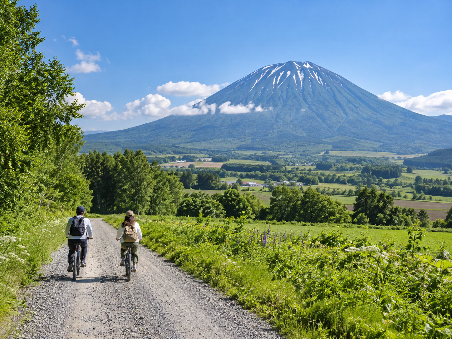 羊蹄山を望む倶知安の自然の中でサイクリングを楽しむ人たちのイメージ